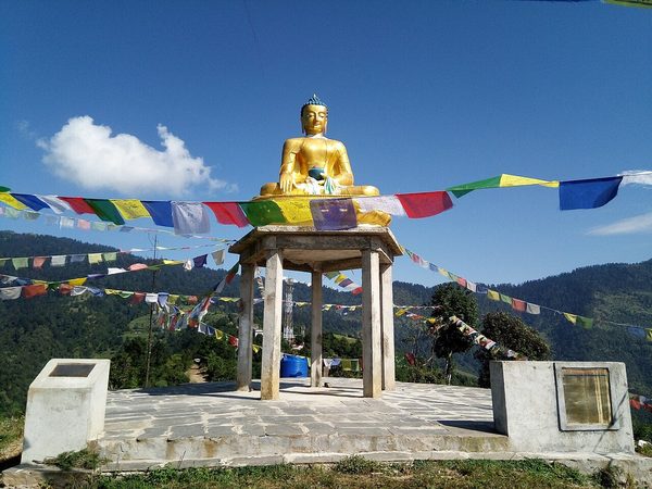 बुद्ध पार्कमा प्रार्थना झण्डाले घेरिएको सुनौलो बुद्ध मूर्ति